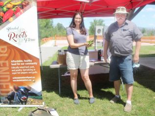 Nicole Connell of Blended Roots Farm shows Mark Revelle of Mark’s Mushrooms a handful of jalapenos at the Frontenac Farmers Market last Saturday in Harrowsmith. Photo/Craig Bakay